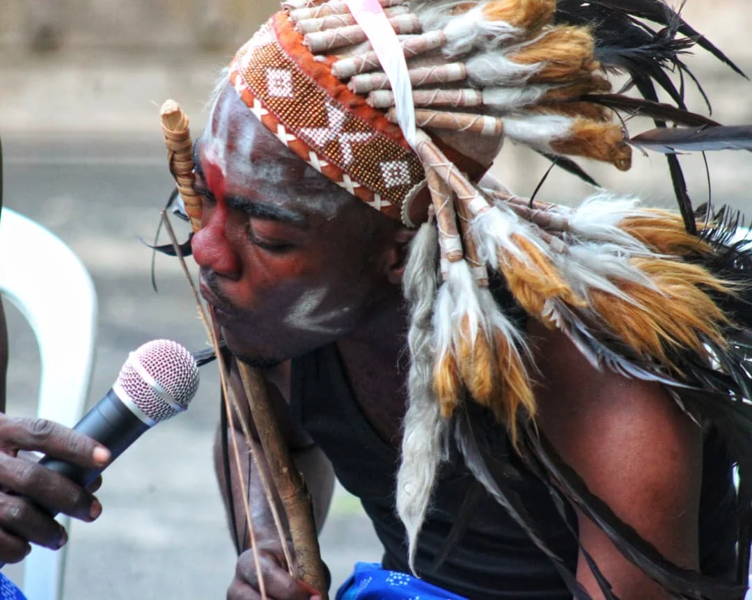 Musicien portant une coiffe de plumes, devant des microphones