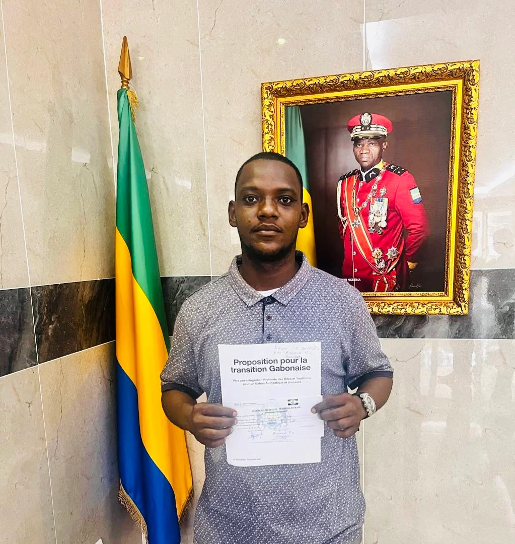 Participant tenant un document devant le drapeau gabonais
